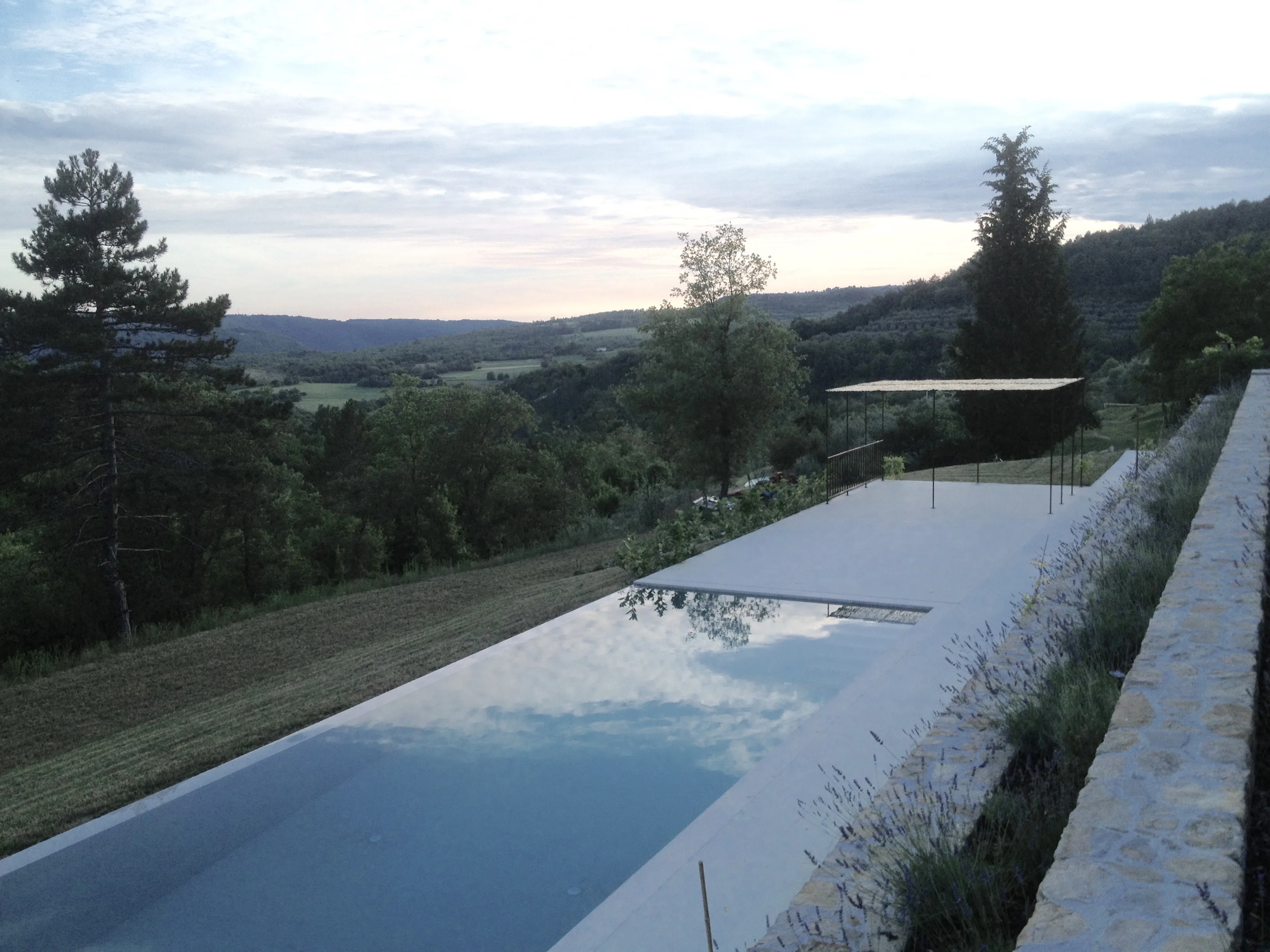 Swimming pool in afternoon sun with oliveyard valley beyond