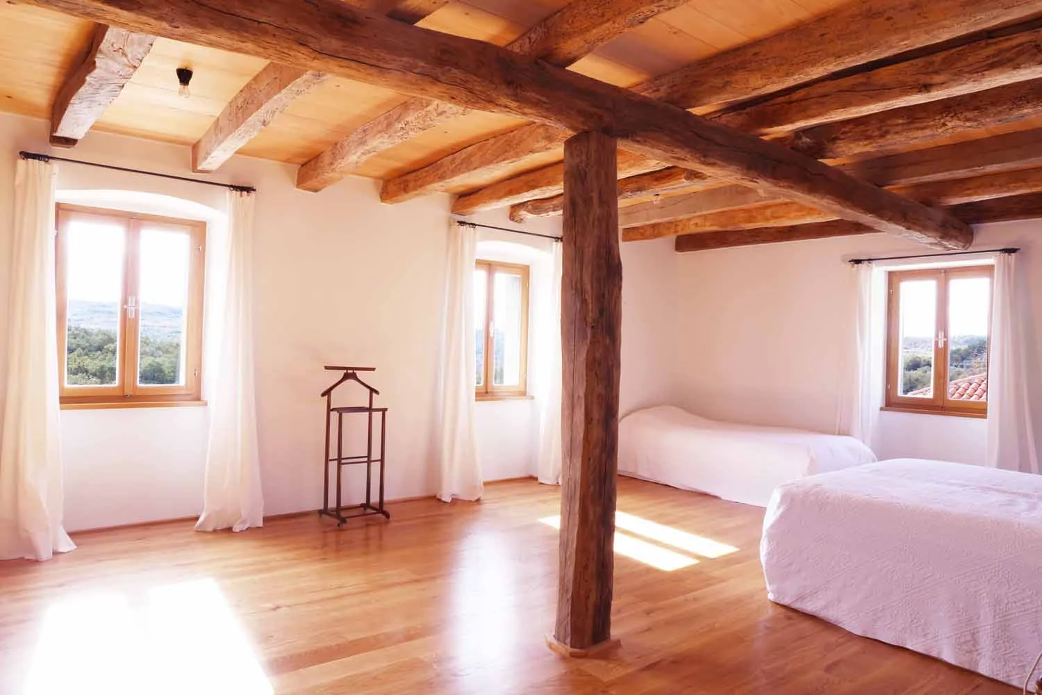 Second bedroom with timber beams and oliveyard views